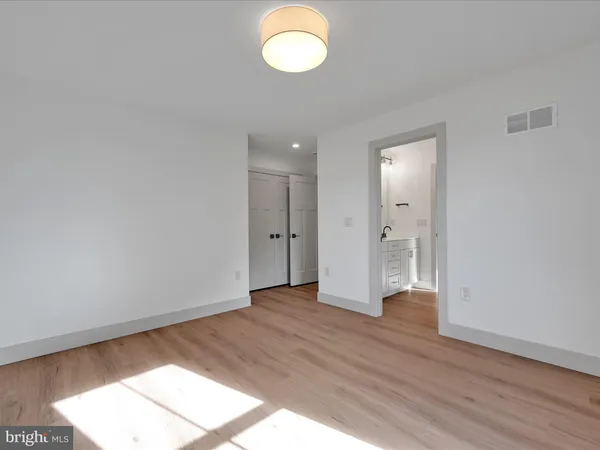a view of an empty room with wooden floor and window