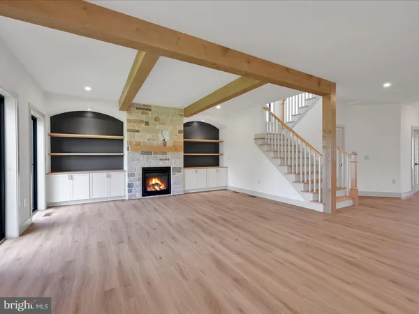 a view of an empty room with wooden floor fireplace and a window