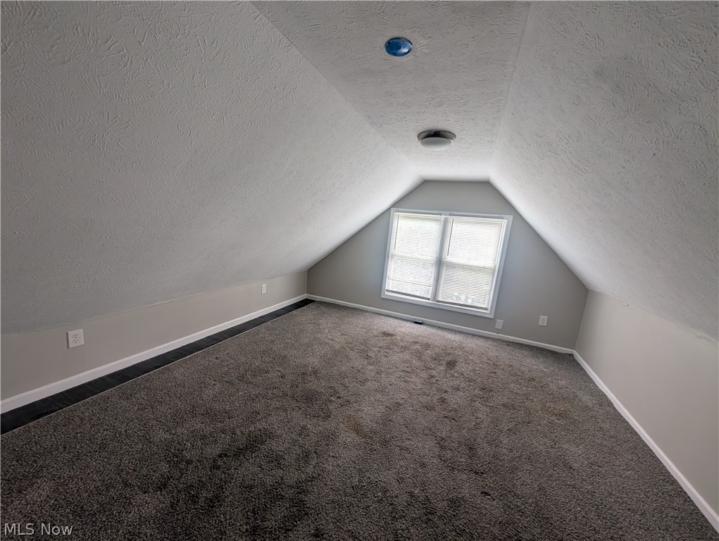 7515 Ottawa Road Cleveland, OH 44105 - Photo 11 of 21 Attic space featuring sloped ceilings, a window with white blinds, and dark gray carpet flooring