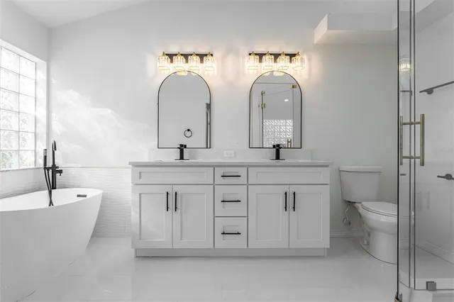 a spacious bathroom with double vanity a toilet a sink and a mirror