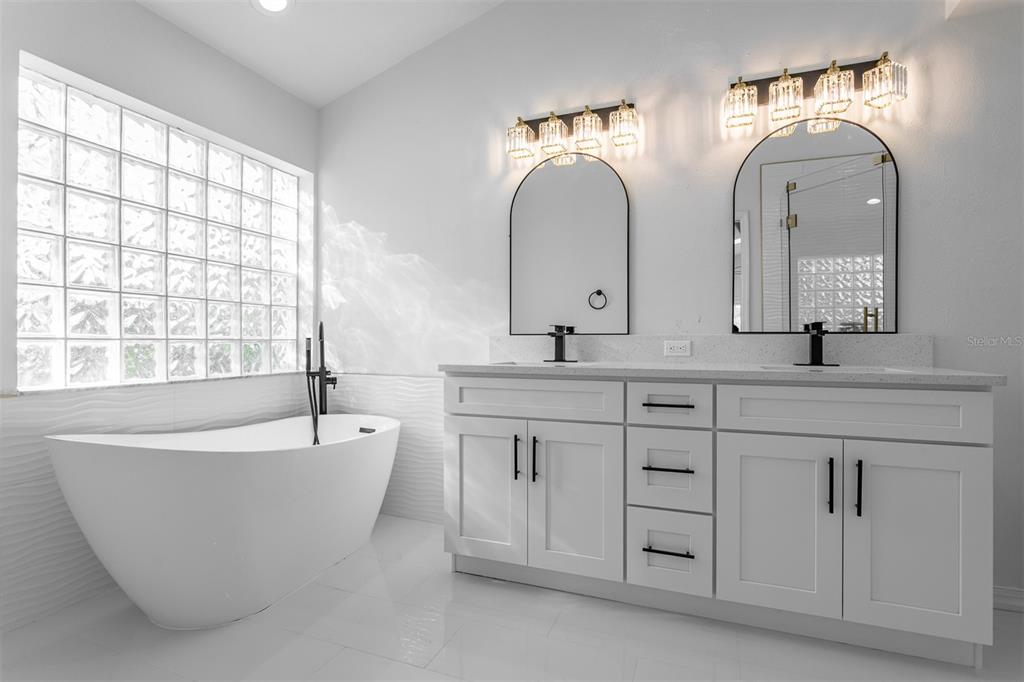 1734 Powder Ridge Drive Valrico, FL 33594 - Photo 16 of 32 a spacious bathroom with double vanity sinks a large mirror and a bathtub
