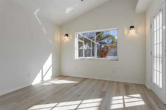 a view of an empty room with wooden floor and a window