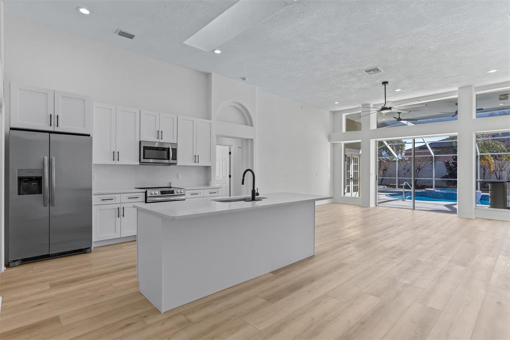 1734 Powder Ridge Drive Valrico, FL 33594 - Photo 9 of 32 a large kitchen with stainless steel appliances a stove a sink dishwasher a refrigerator white cabinets and wooden floor