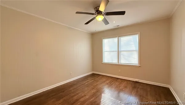 an empty room with wooden floor fan and windows