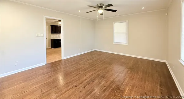 an empty room with wooden floor and windows