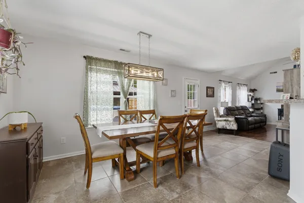 a view of a dining room and livingroom with furniture wooden floor a rug a flat screen tv and a painting
