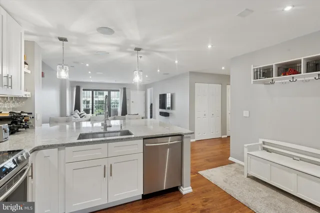a kitchen with a sink dishwasher a stove and white cabinets with wooden floor