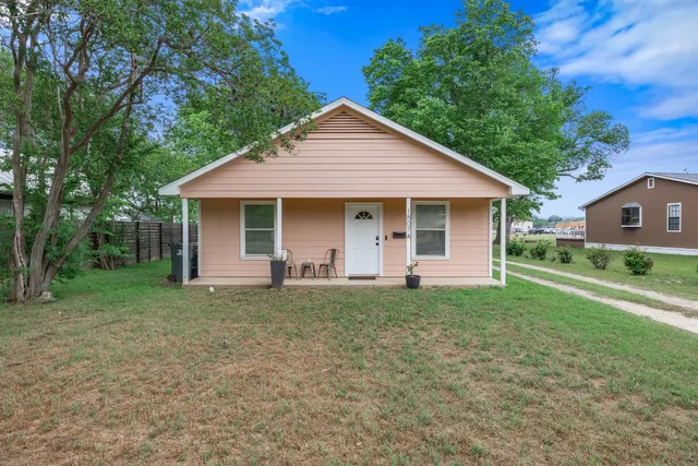 a front view of a house with a garden and trees