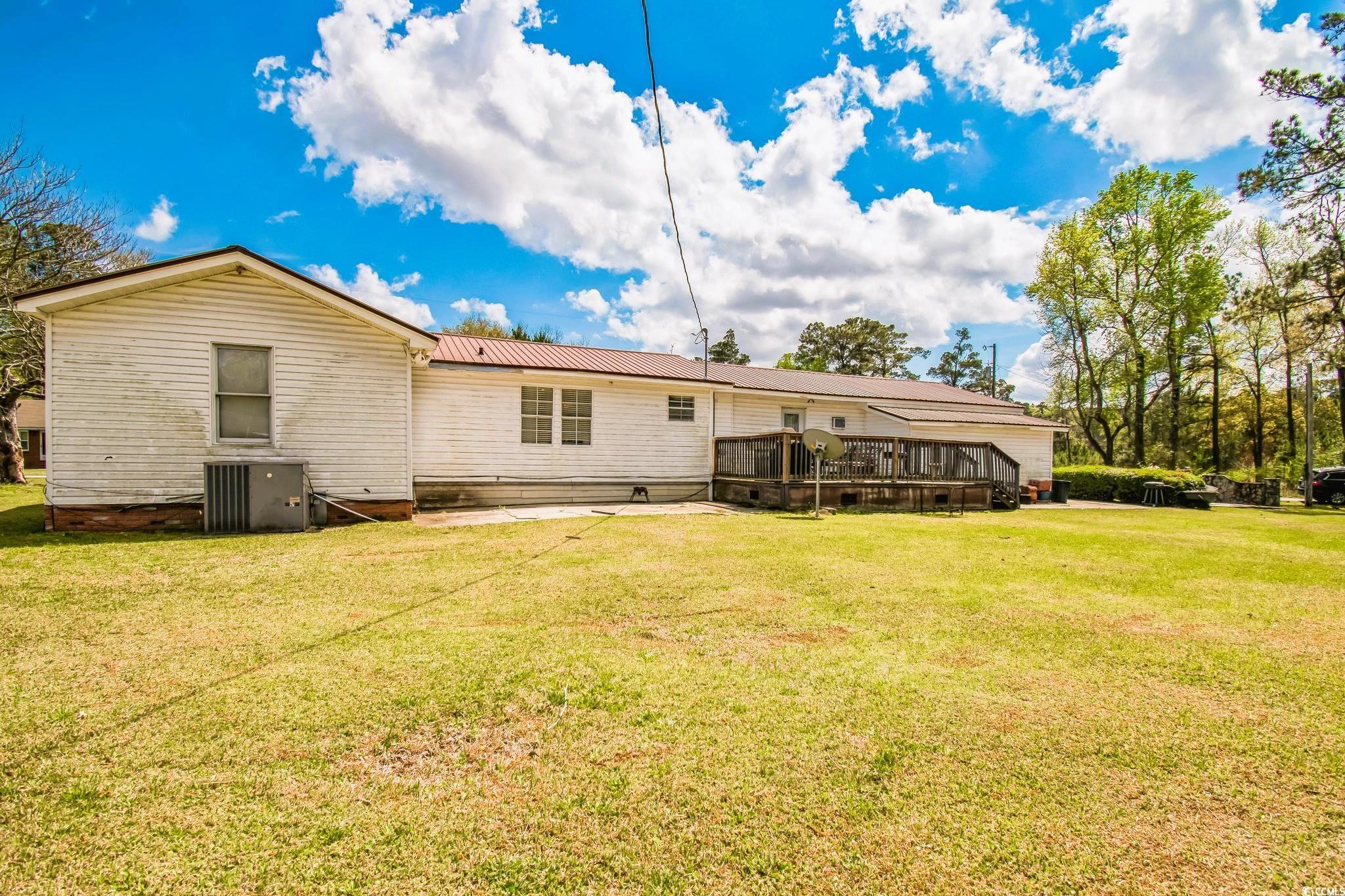 54 Juniper Place Georgetown, SC 29440 - Photo 10 of 11 Rear view of property featuring a yard, a wooden deck, and a metal roof