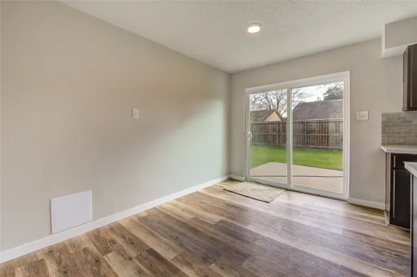 a view of an empty room with wooden floor and a fireplace