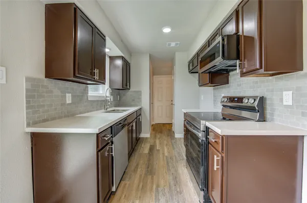 a kitchen with stainless steel appliances granite countertop wooden cabinets a stove top oven a sink and dishwasher