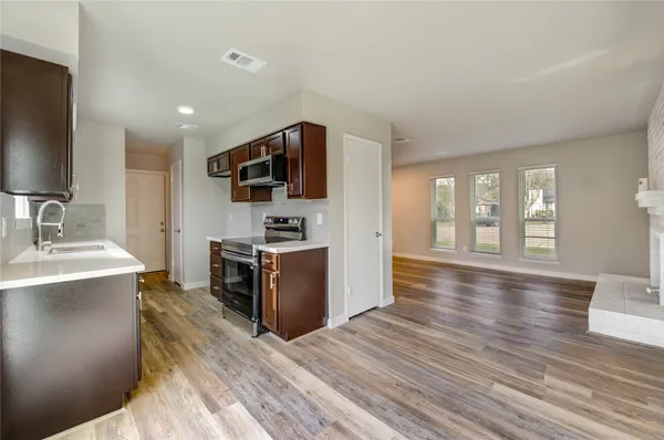 a kitchen with stainless steel appliances a stove top oven a sink dishwasher a refrigerator and cabinets with wooden floor