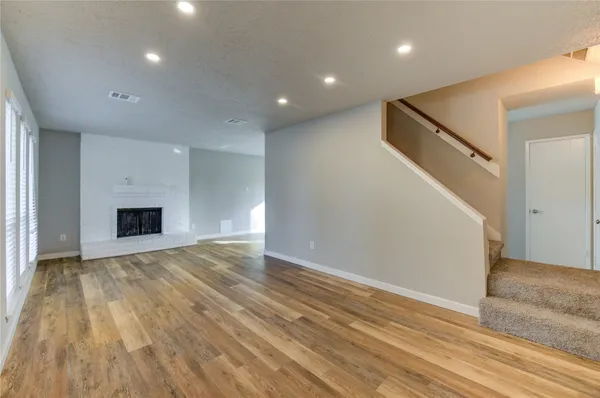 an empty room with wooden floor and fireplace