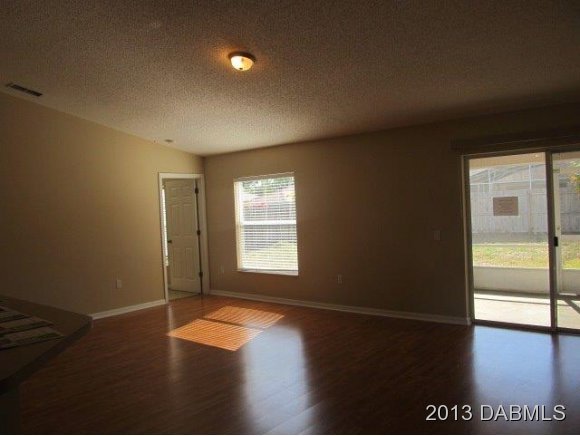 304 Mariners Gate Drive Edgewater, FL 32141 - Photo 3 of 16 an empty room with wooden floor and windows with curtains