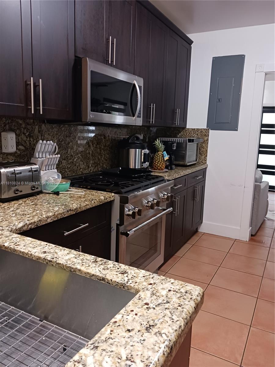 3429 Southwest 23rd Terrace Miami, FL 33145 - Photo 15 of 32 a kitchen with stainless steel appliances granite countertop a stove a sink and a microwave