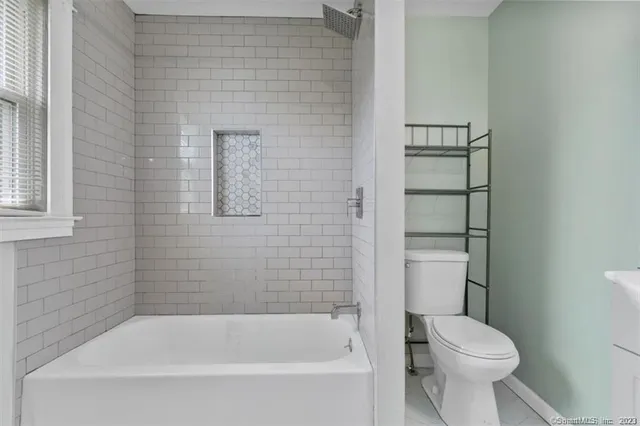 a white toilet sitting next to a bath tub
