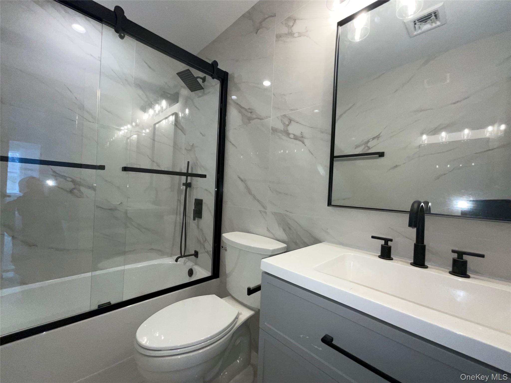 89 B Mount Sinai-Coram Road Coram, NY 11727 - Photo 22 of 22 a bathroom with a toilet a sink and a large mirror