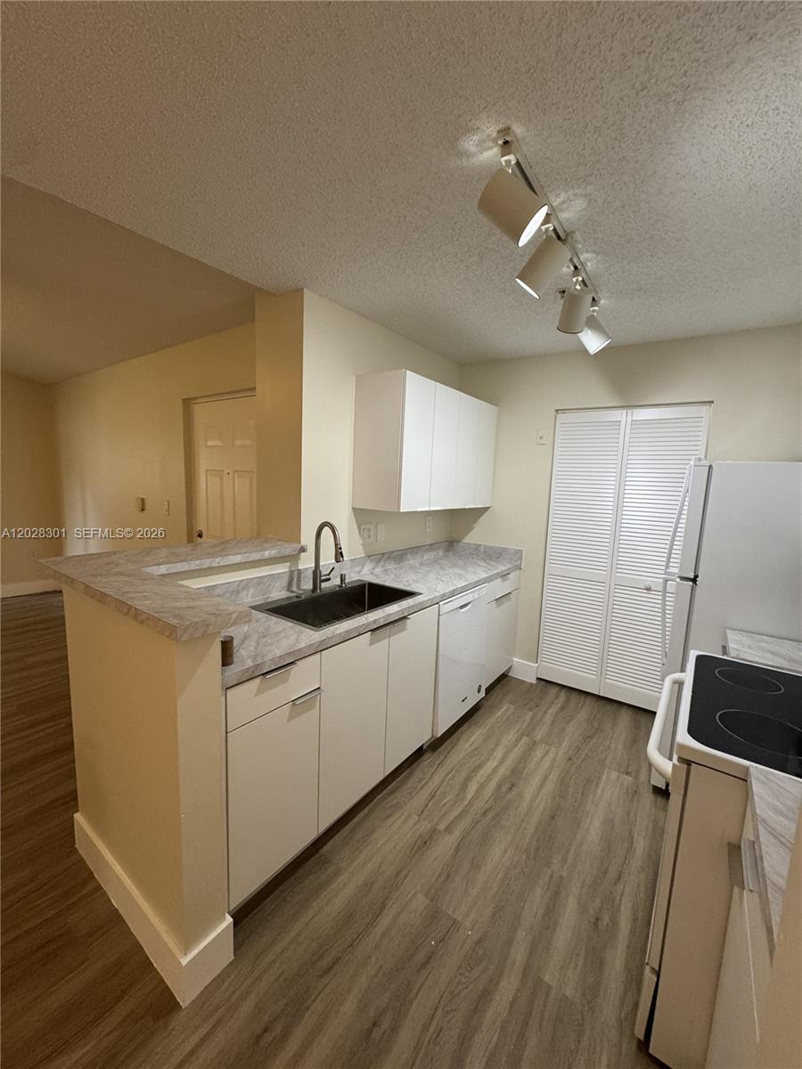 2021 Renaissance Boulevard, Unit 201 Miramar, FL 33025 - Photo 7 of 26 a large white kitchen with a sink stainless steel appliances and cabinets