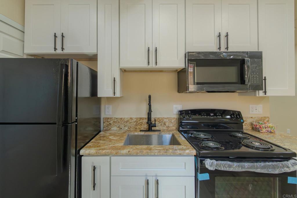 1174 Sea Strand Lane San Diego, CA 92154 - Photo 3 of 32 a kitchen with kitchen island a sink stainless steel appliances and cabinets