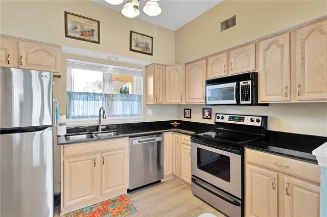 a kitchen with granite countertop a refrigerator sink and white cabinets
