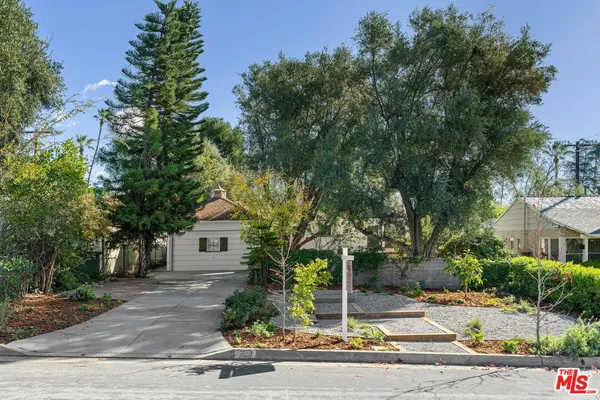 a front view of a house with a tree