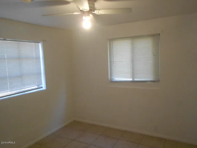 an empty room with a fan & a window