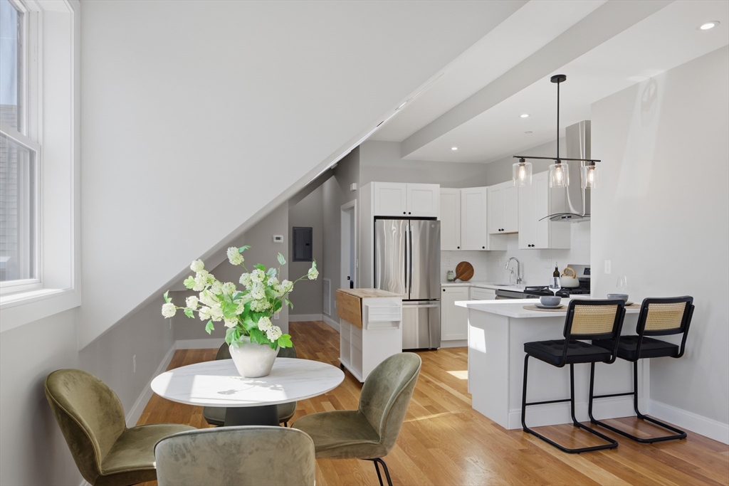 174 Walnut Street, Unit 3 Somerville, MA 02145 - Photo 22 of 38 a kitchen with stainless steel appliances kitchen island granite countertop a dining table and chairs