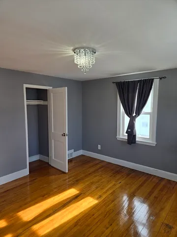 a view of an empty room with window and wooden floor