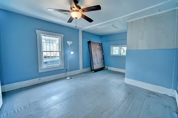 an empty room with windows and fan