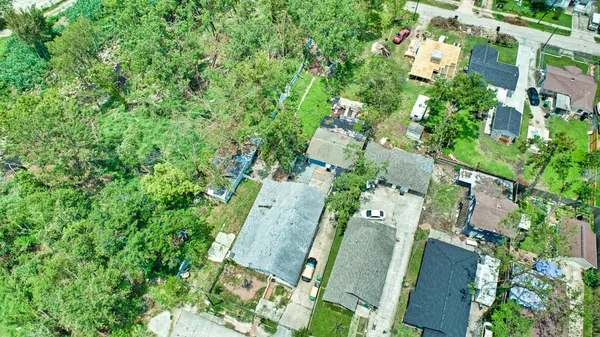 an aerial view of a residential houses with outdoor space and trees all around