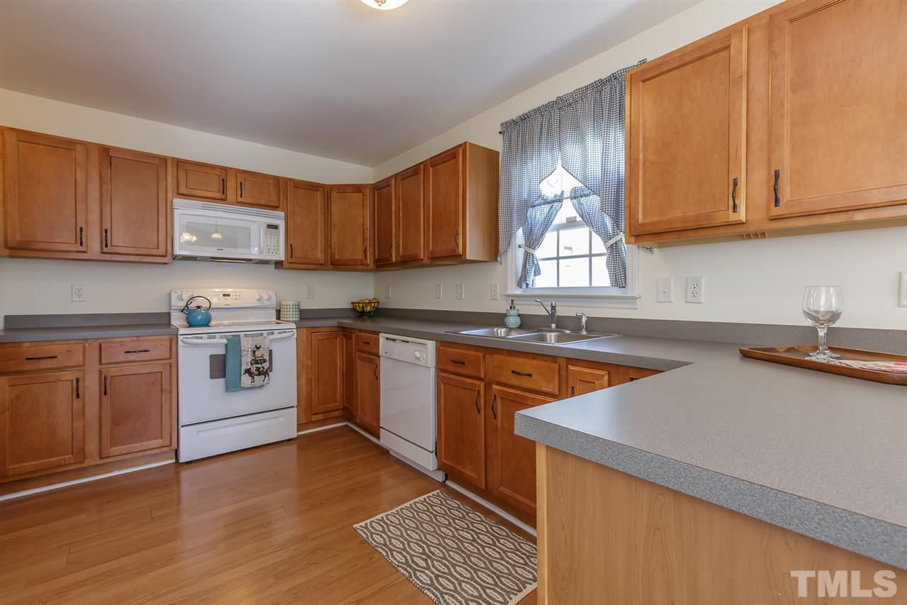 4105 Neal Road, Unit C Durham, NC 27705 - Photo 6 of 22 a kitchen with stainless steel appliances granite countertop a stove a sink dishwasher and a microwave oven with wooden cabinets