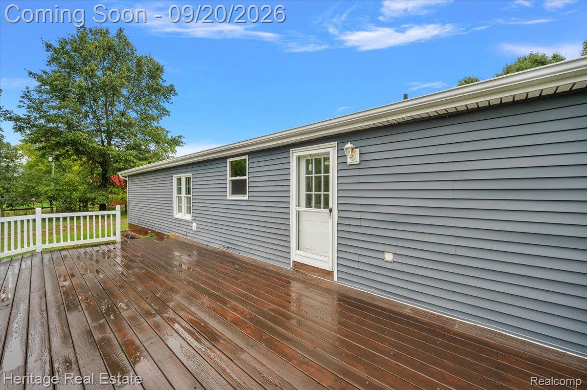 3337 Le Valley Road Columbiaville, MI 48421 - Photo 32 of 57 Spacious composite deck featuring rich wood-finish flooring and white railings, complemented by gray horizontal vinyl siding and multiple windows