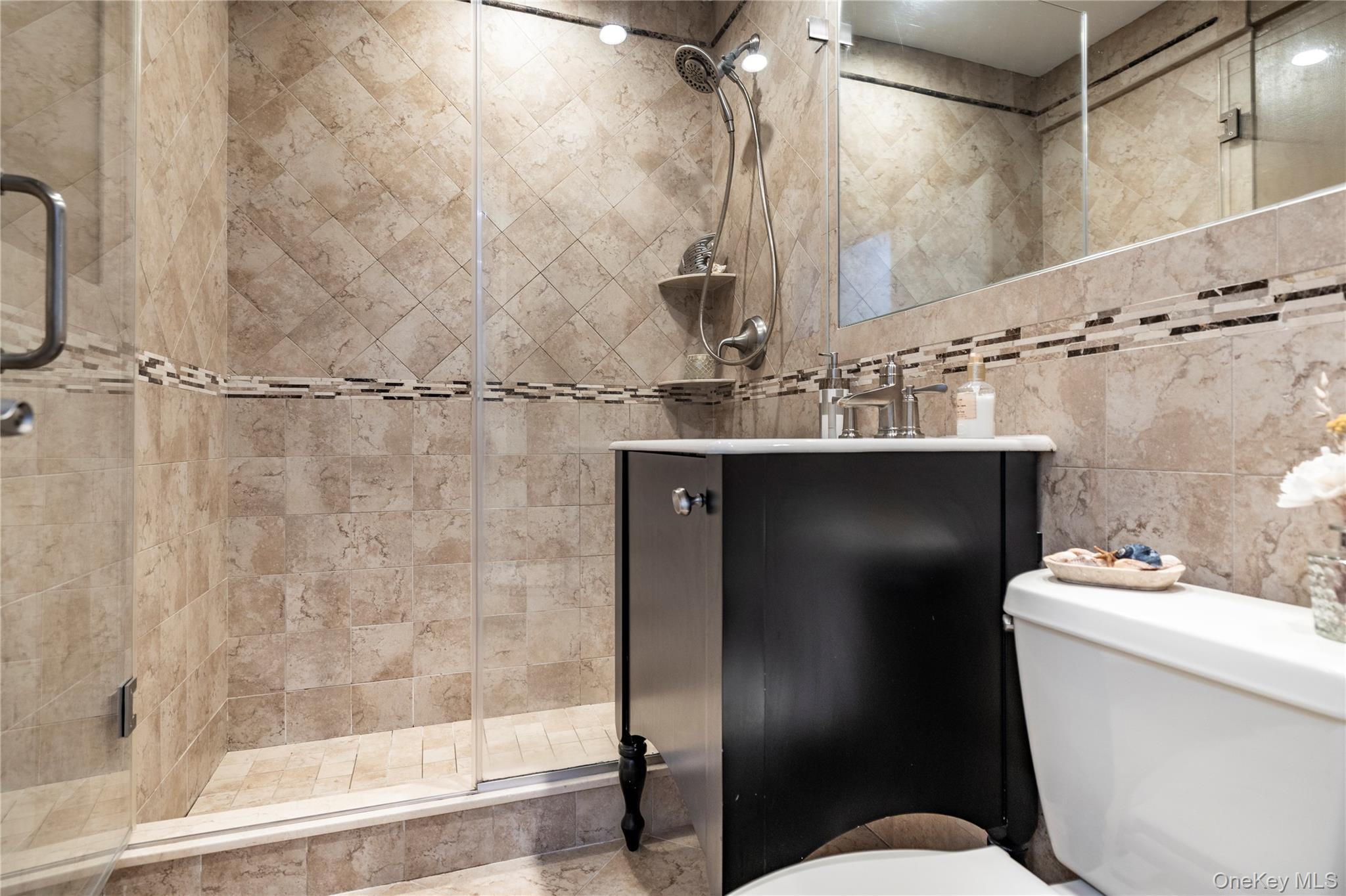 522 Shore Road, Unit 4W Long Beach, NY 11561 - Photo 14 of 33 Bathroom with toilet, vanity, a stall shower, and tile walls