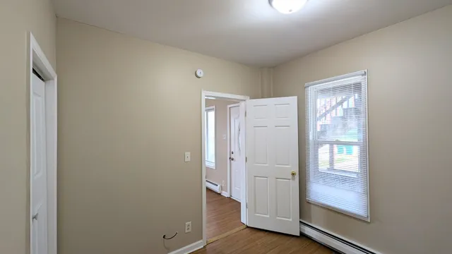 a view of an empty room with wooden floor and a window