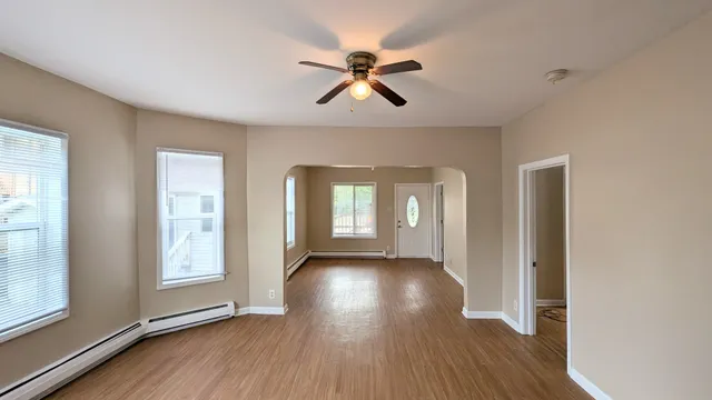 a view of empty room with wooden floor and fan