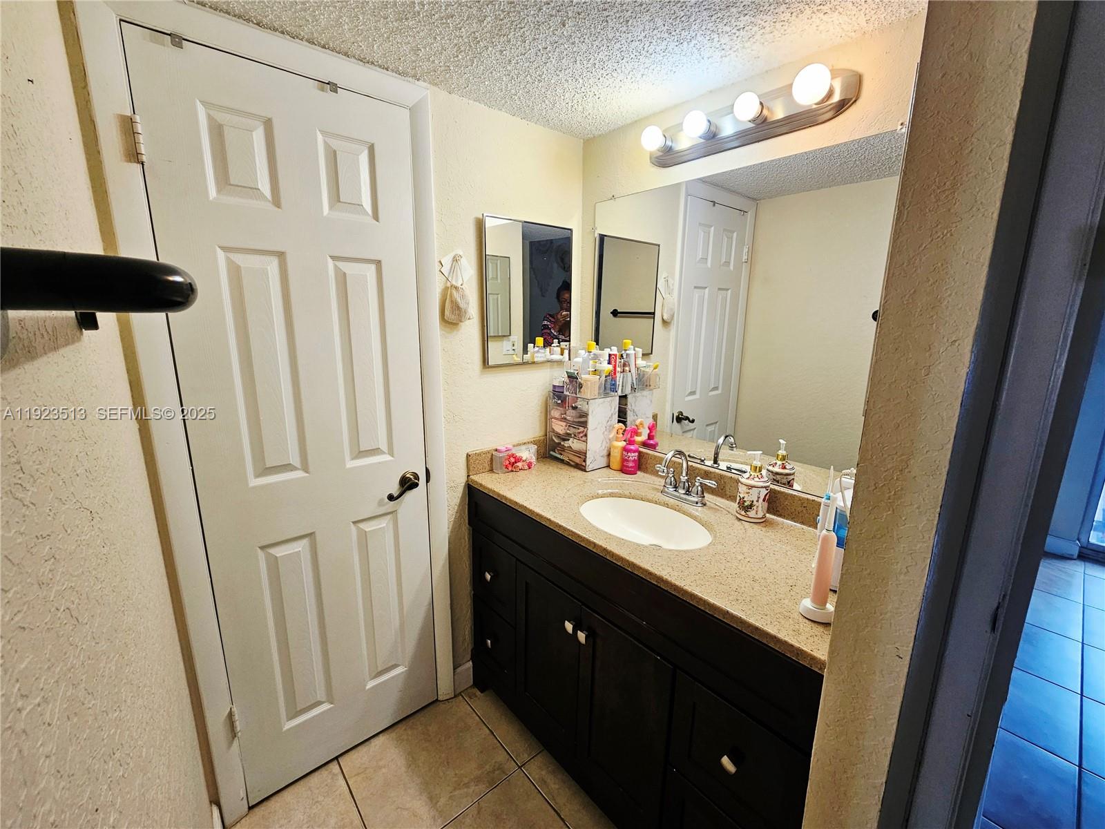 8401 West Sample Road, Unit 10 Coral Springs, FL 33065 - Photo 12 of 17 a bathroom with a sink a mirror a vanity and a shower