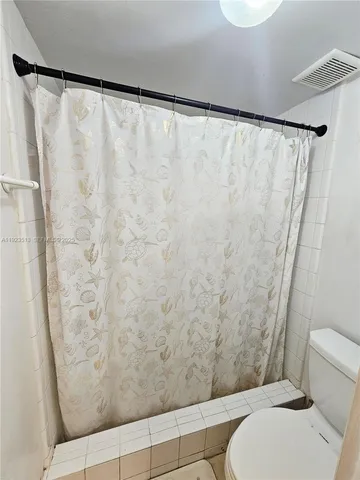 a bathroom with a toilet and a shower curtain