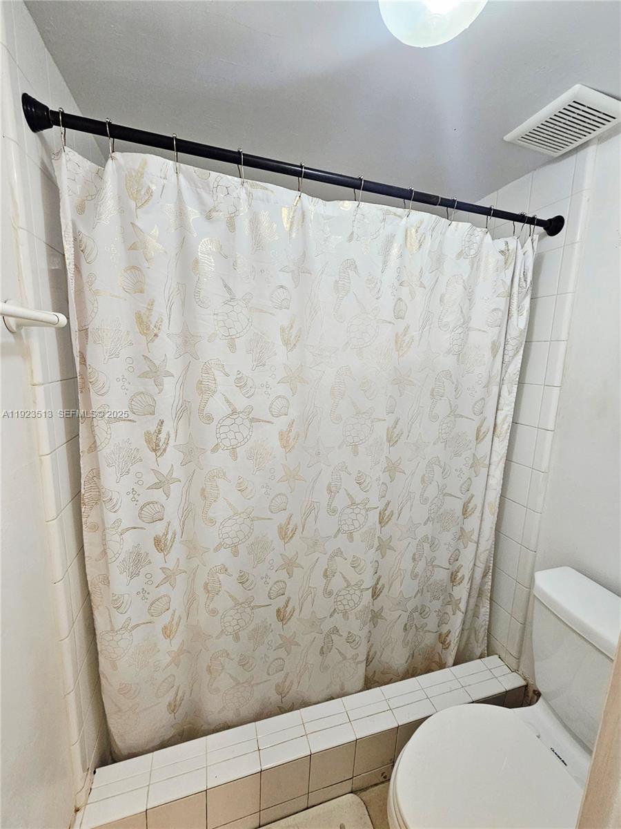 8401 West Sample Road, Unit 10 Coral Springs, FL 33065 - Photo 13 of 17 a bathroom with a toilet and a shower curtain