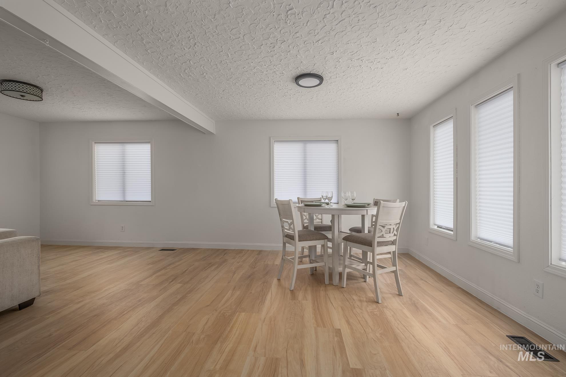 61 Southwest 4th Street Ontario, OR 97914 - Photo 6 of 42 Open-concept living space featuring light wood-finish flooring, white walls, and multiple windows with blinds