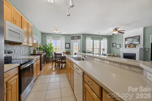 a large kitchen with granite countertop a large counter top space a sink stainless steel appliances and cabinets