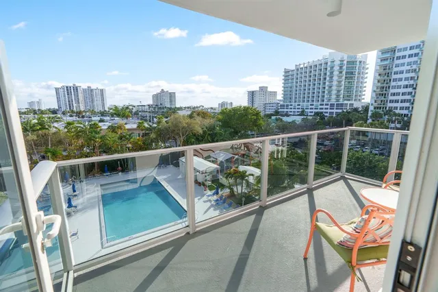a view of a city from a balcony with wooden chairs