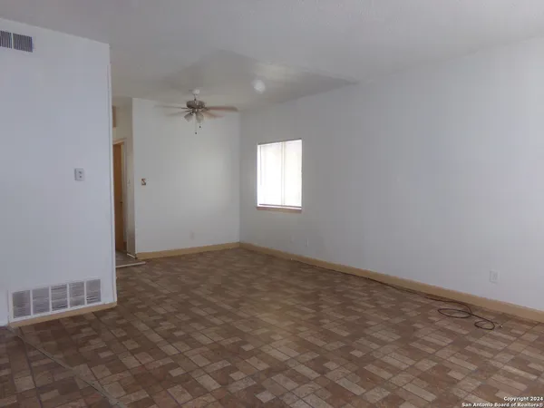 an empty room with windows and fan