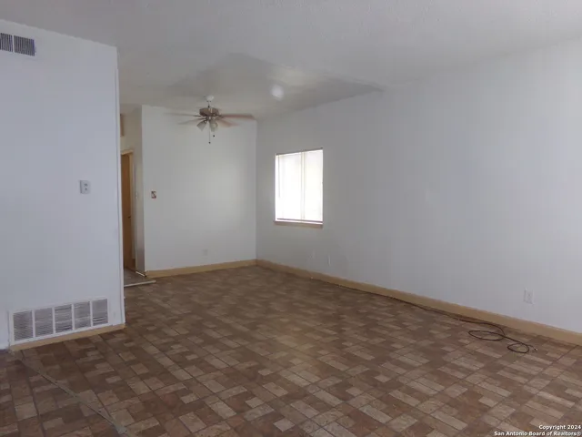 an empty room with windows and fan