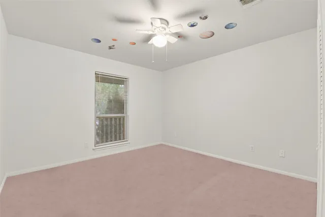 an empty room with a window and a fan