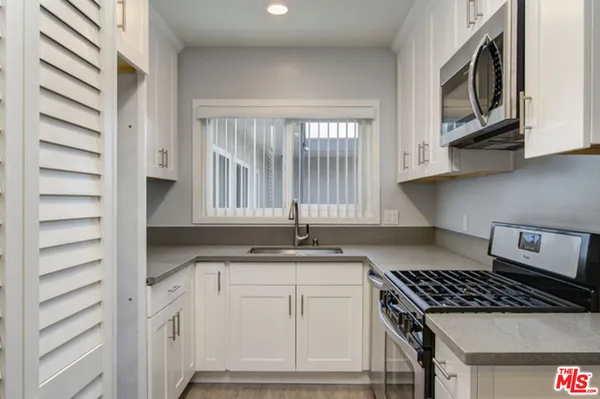 a kitchen with granite countertop a sink stove and cabinets