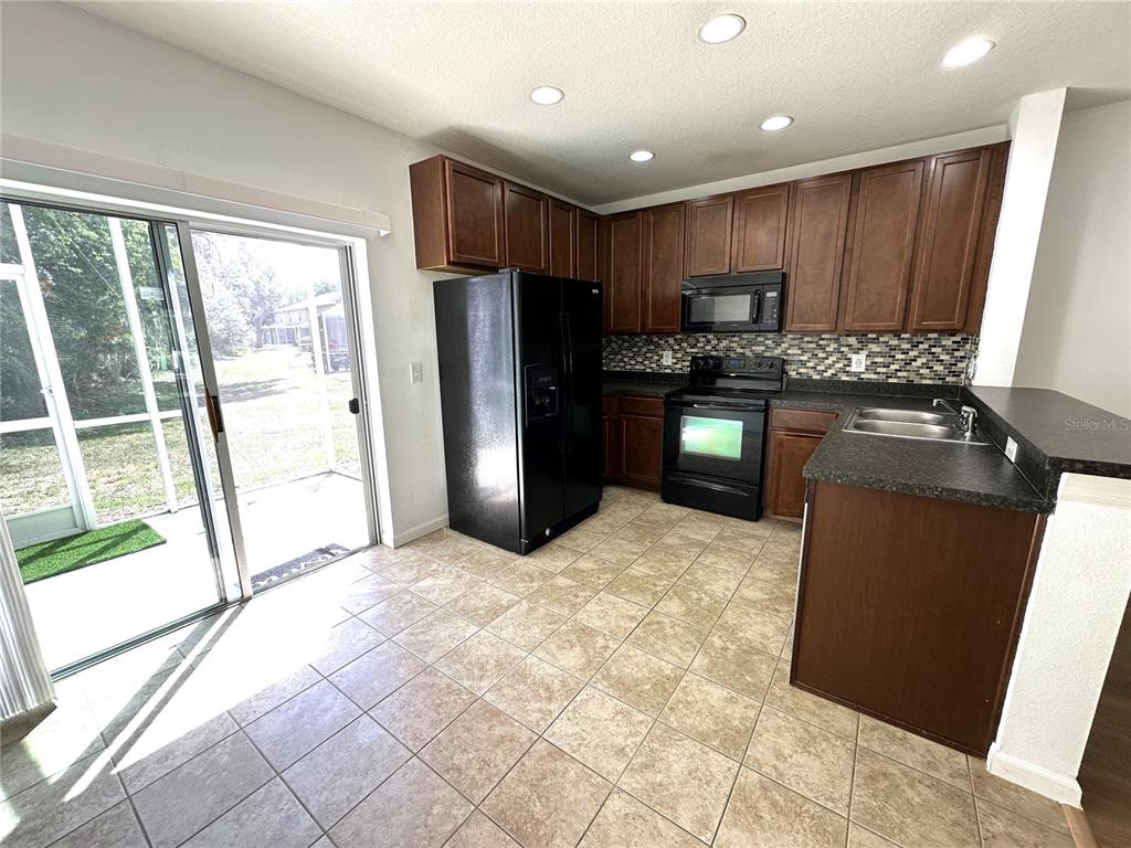 15816 Fishhawk View Drive Lithia, FL 33547 - Photo 7 of 30 a kitchen with granite countertop a refrigerator a stove top oven and a sink with granite countertops