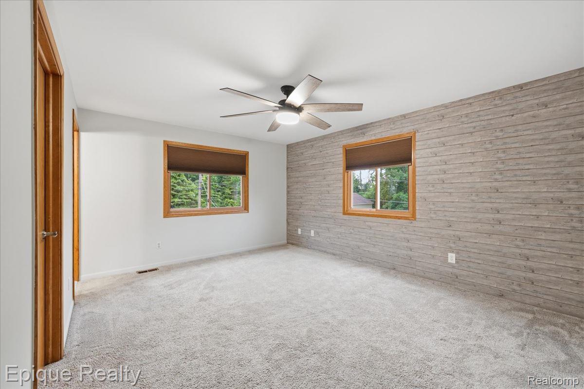 1221 Rhodes Road Lake Orion, MI 48360 - Photo 31 of 72 Spacious room featuring a shiplap accent wall, light gray carpeting, and two windows with wood-finish trim