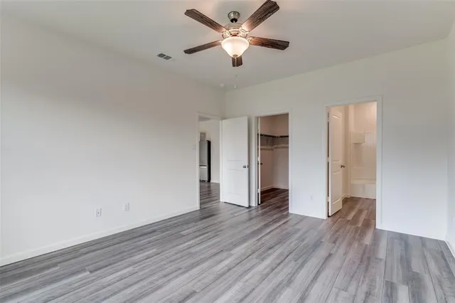 a view of an empty room and window a ceiling fan and wooden floor