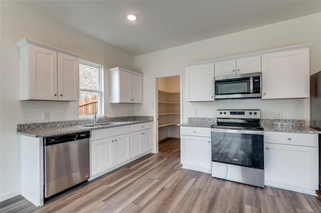 a kitchen with stainless steel appliances granite countertop a stove a sink and a microwave