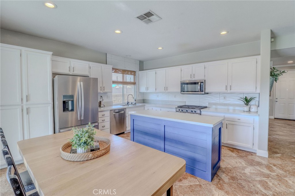 729 Windbound Avenue Beaumont, CA 92223 - Photo 28 of 73 a kitchen with stainless steel appliances granite countertop a white refrigerator a stove a microwave and a dining table with wooden floor